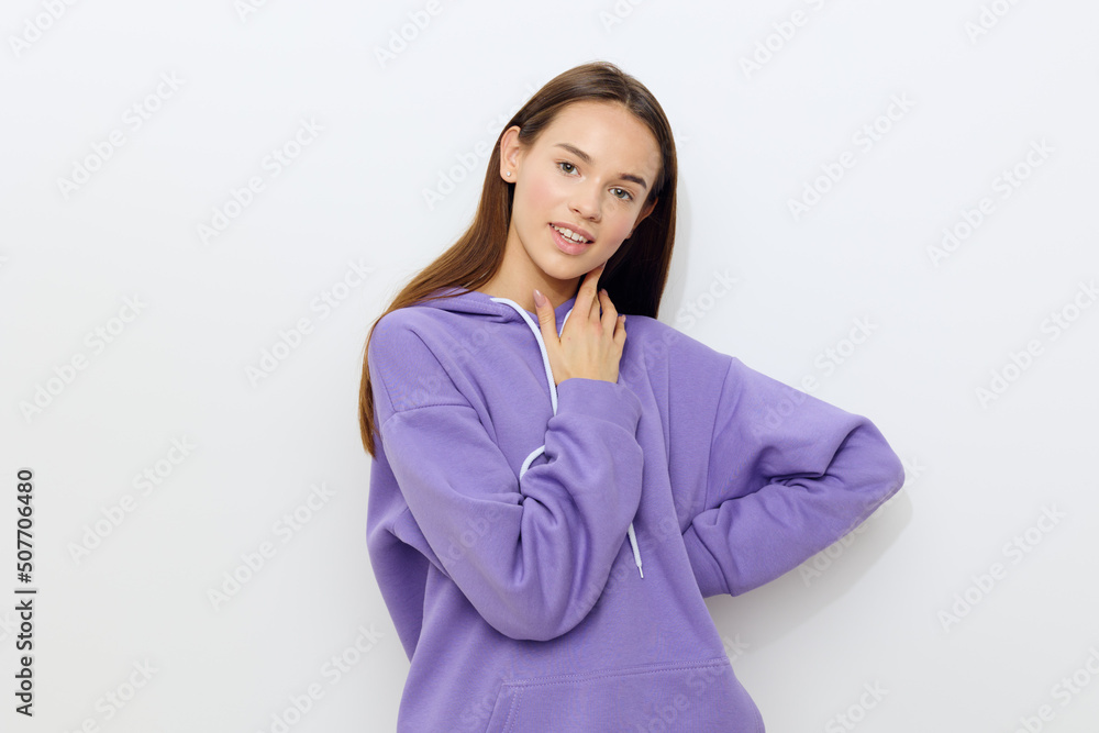an emotional woman stands on a white background in a purple tracksuit slightly leans one hand against her face, putting the other on her belt, smiling sweetly an emotional woman stands on a white background in a purple tracksuit slightly leans one hand against her face, putting the other on her belt, smiling sweetly