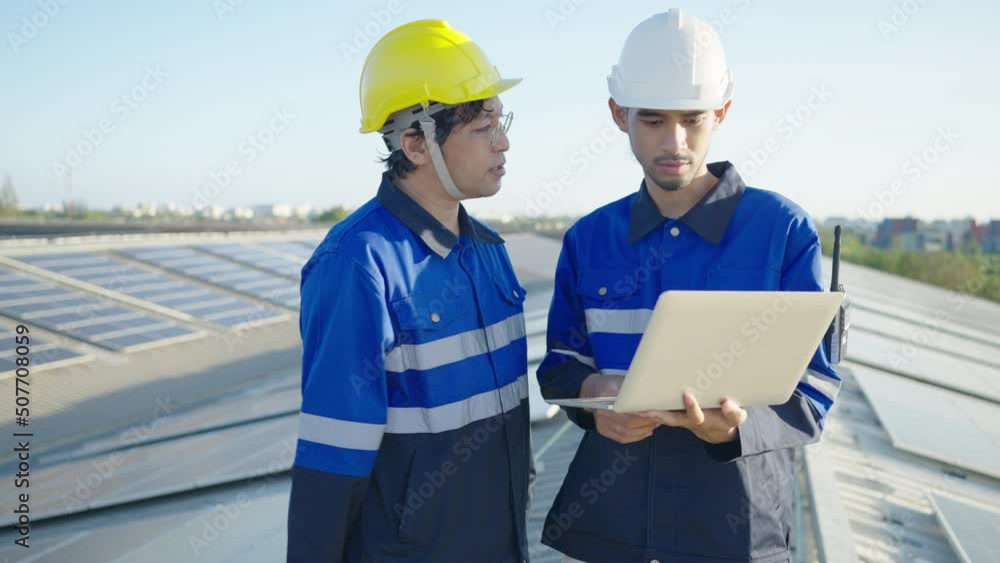 Two Asian technician installing inspection or repair solar cell panels on background field of photovoltaic solar panels solar cells on roof top factory. Two Asian technician installing inspection or repair solar cell panels on background field of photovoltaic solar panels solar cells on roof top factory.