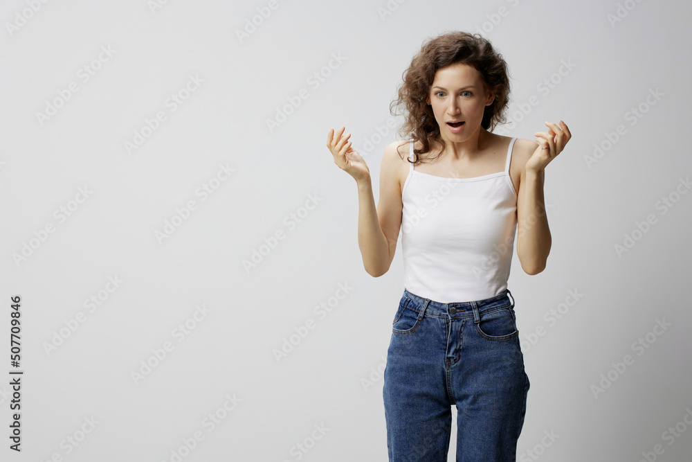 Confused shocked curly beautiful woman in basic white t-shirt raise hands up open mouth posing isolated on over white background. People Emotions Lifestyle. I can not believe it concept. Copy space Confused shocked curly beautiful woman in basic white t-shirt raise hands up open mouth posing isolated on over white background. People Emotions Lifestyle. I can not believe it concept. Copy space