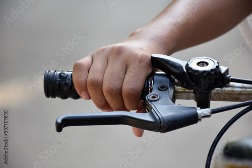 Closeup view of handlebar of bicycle which has hand of kid holding it, soft and selective focus.