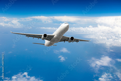 A white passenger plane soars up in the blue sky. Aircraft front view.