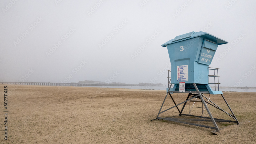 Lifeguard hut on beach in Santa Barbara with fog-shrouded pier in background