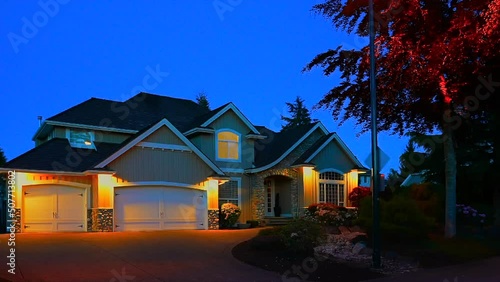 Establishing shot of two story stucco luxury house with garage door, big tree and nice landscape at night in Vancouver, Canada, North America. Night time on May 2022. ProRes 422 HQ.