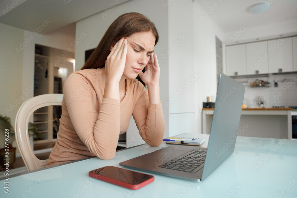 Stressed young woman suffering from headache after computer work Stressed young woman suffering from headache after computer work