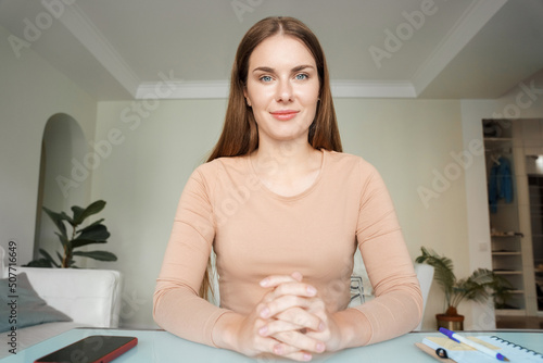 Portrait of young woman talking to camera making video conference