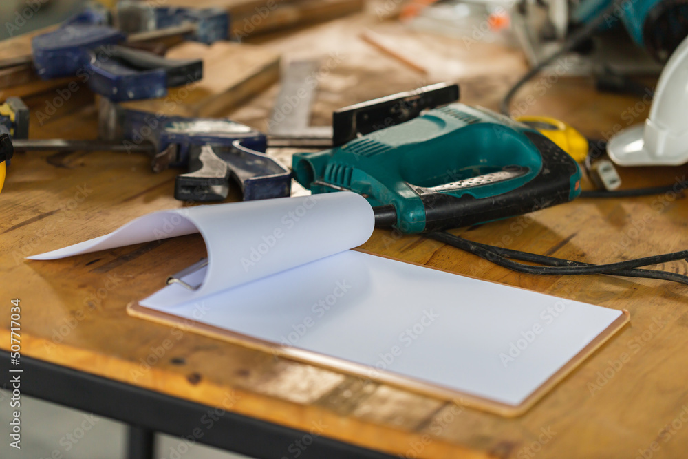 Construction concepts. Wooden clipboard with blank paper on the engineering desks. Wooktools on desks at construction site Construction concepts. Wooden clipboard with blank paper on the engineering desks. Wooktools on desks at construction site