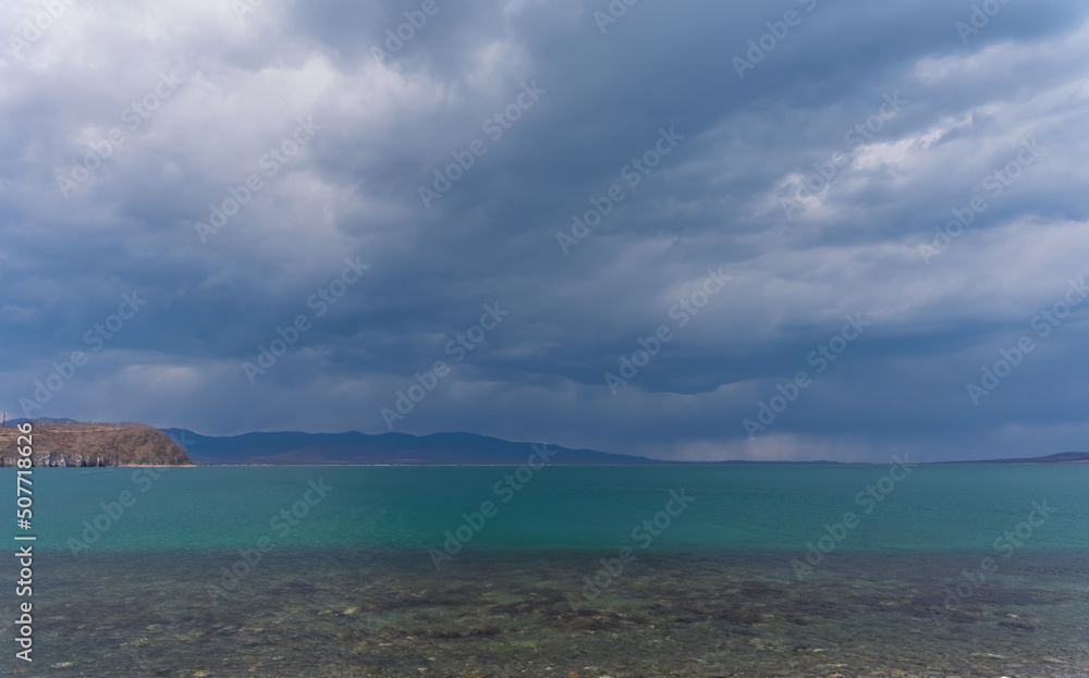 Dark blue clouds and sea or ocean water surface with dramatic seascape