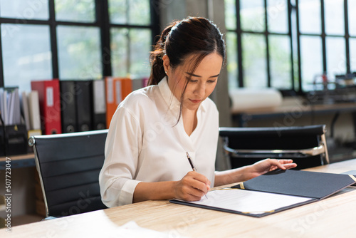 Φωτογραφία Asian business female project manager reading document report at desk in the office