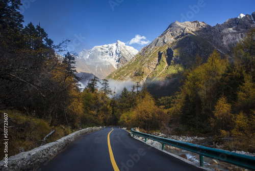 Wenzhou Waterfall in Aba, Sichuan Province, with yellow leaves, highway, distant mountains and white clouds photo