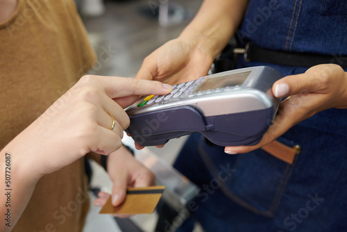 Hands of client entering pin code when paying with credit card for haircut