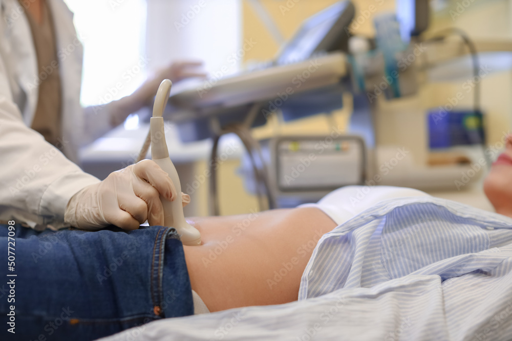 Fototapeta premium Young pregnant woman undergoing ultrasound scan in modern clinic