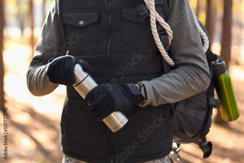 Male tourist with thermos in forest