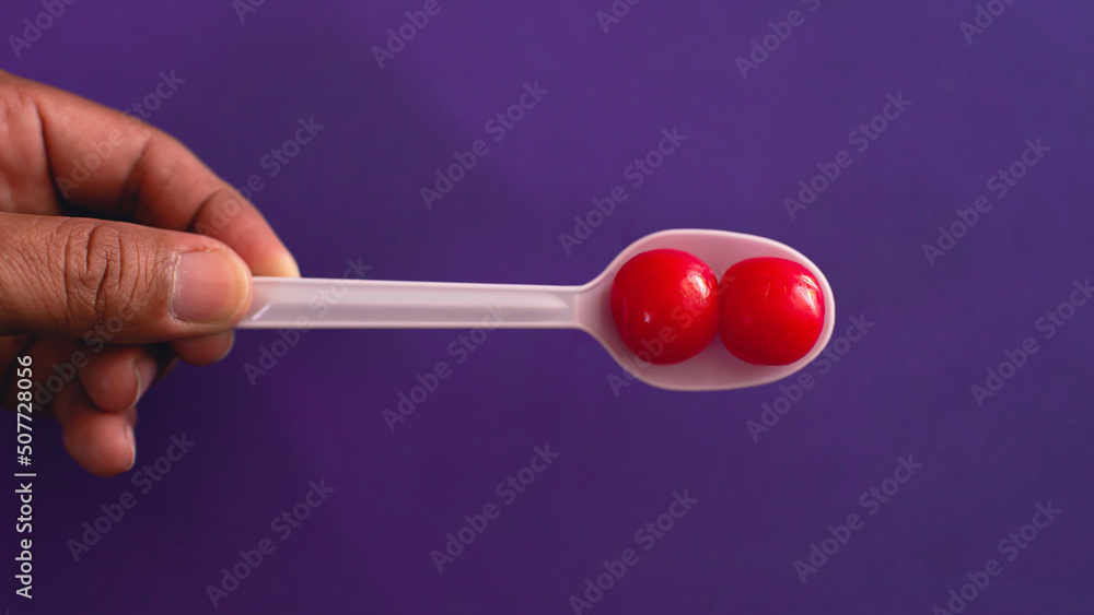 Soaked fruit has a sweet taste with a bright red color. in a white spoon purple background Soaked fruit has a sweet taste with a bright red color. in a white spoon purple background