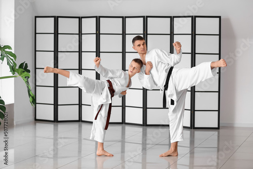 Boy practicing karate with instructor in dojo photo