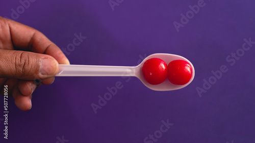 Soaked fruit has a sweet taste with a bright red color. in a white spoon purple background