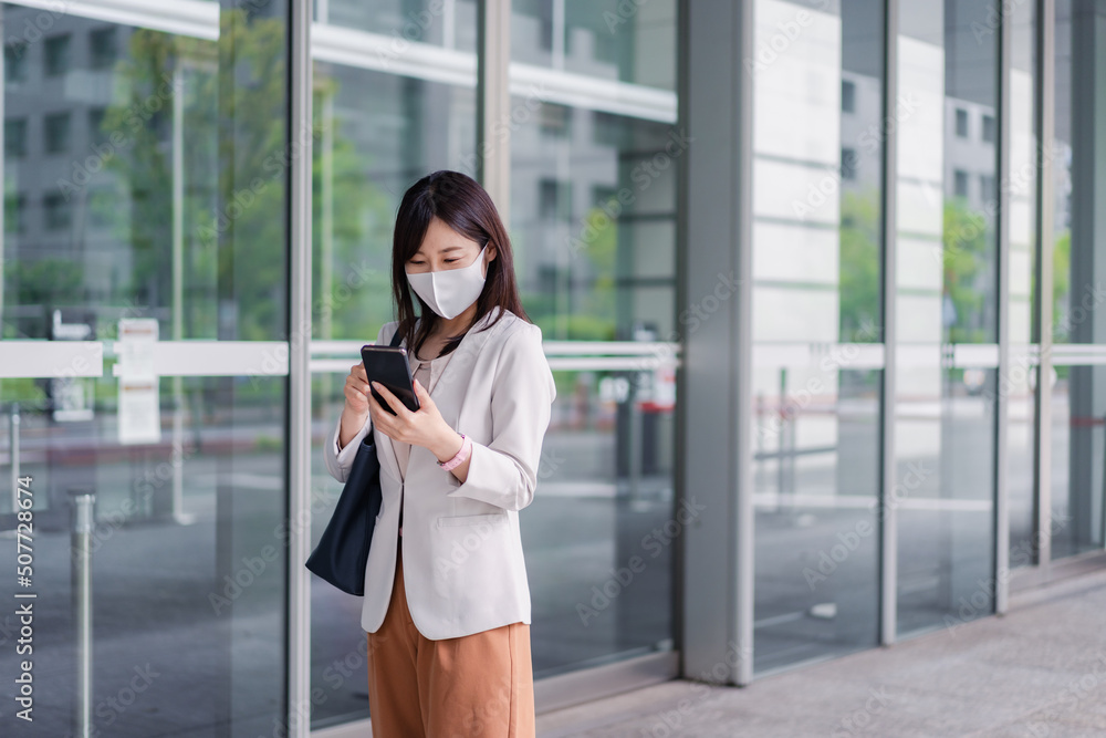 マスクをしてスマホを使う若い女性