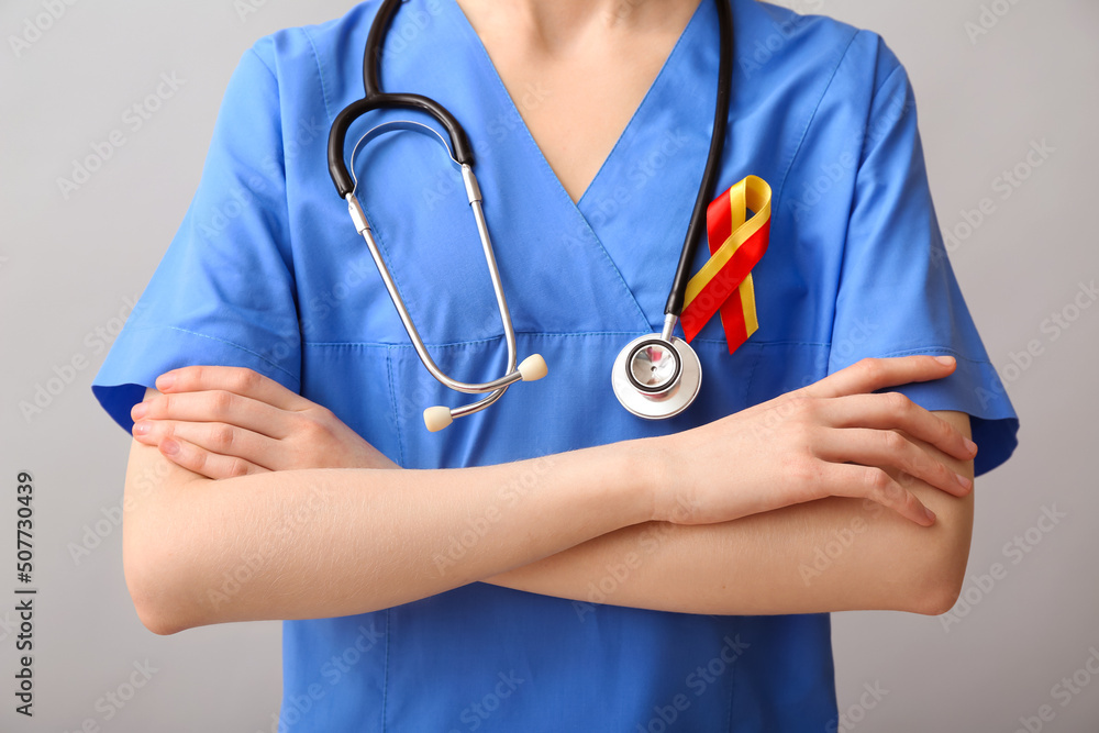 Female doctor with awareness ribbon and stethoscope on grey background. Hepatitis concept Female doctor with awareness ribbon and stethoscope on grey background. Hepatitis concept