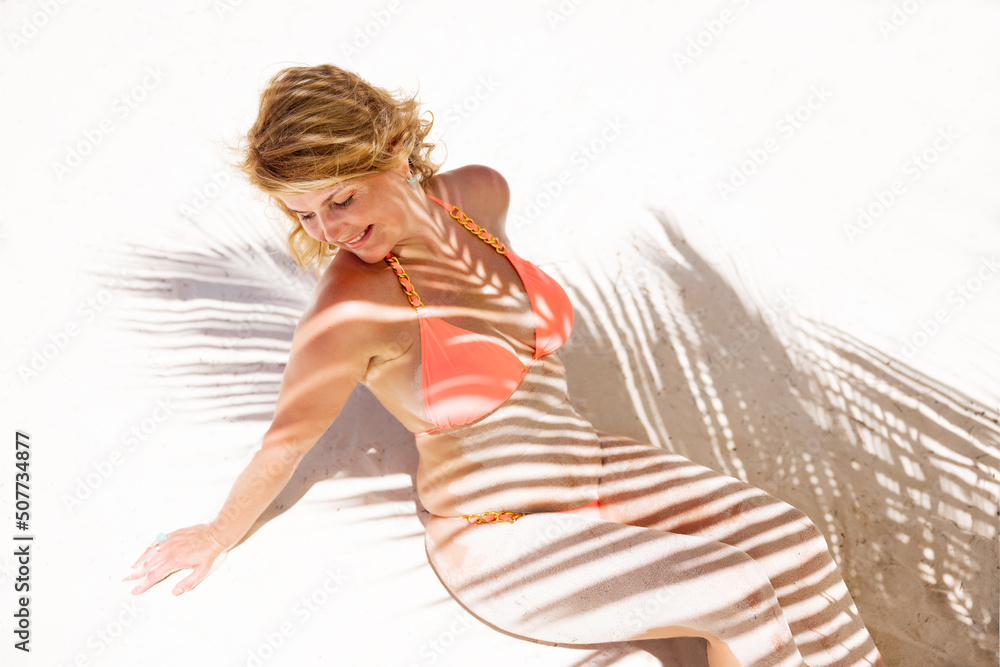 Woman sunbathing on tropical beach under palm tree leaves Woman sunbathing on tropical beach under palm tree leaves