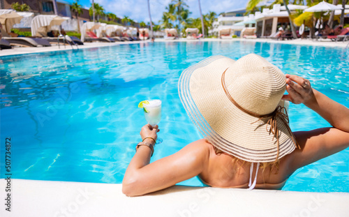 Photography Woman holding glass of cocktail while relaxing in swimming pool in resort on vac