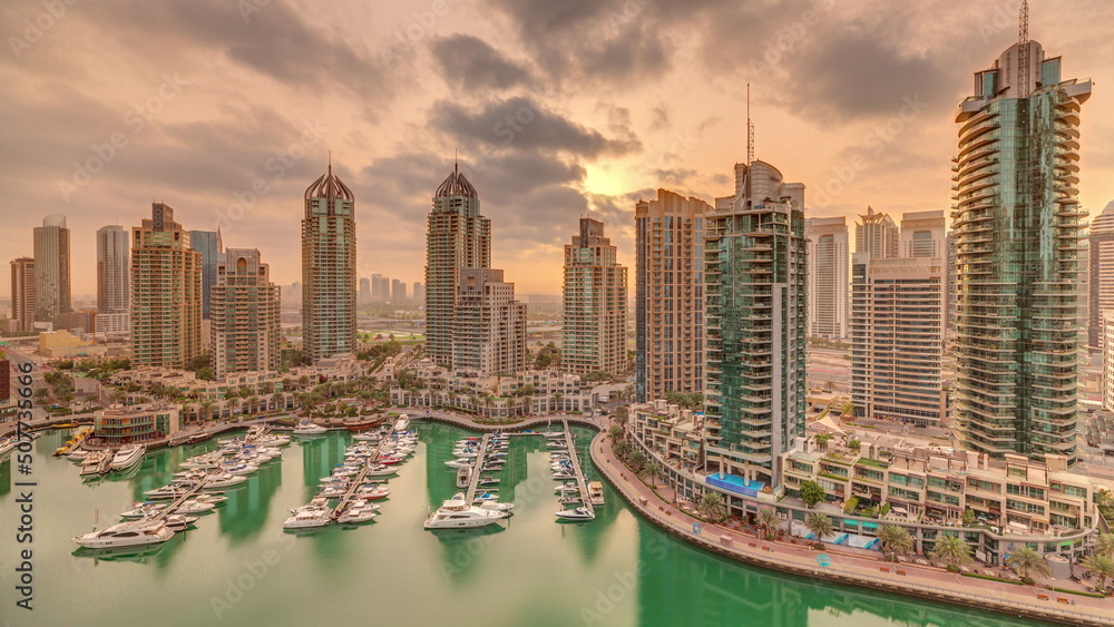 Obraz premium Sunrise over Dubai Marina luxury tourist district with skyscrapers and towers around canal aerial timelapse