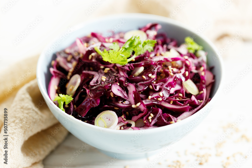 red cabbage salad, coleslaw, in a bowl on white wooden table. red cabbage salad, coleslaw, in a bowl on white wooden table.