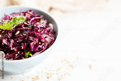 red cabbage salad  coleslaw  in a bowl on white wooden table.