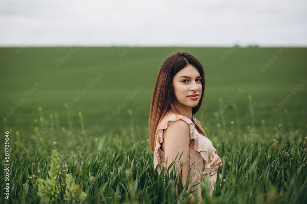 Beautiful girl is relaxing while sitting on green field Beautiful girl is relaxing while sitting on green field