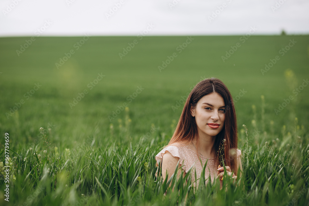 Beautiful girl is relaxing while sitting on green field Beautiful girl is relaxing while sitting on green field