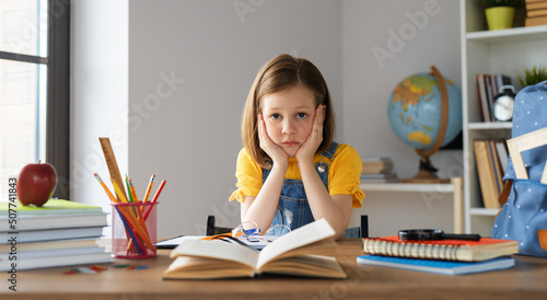 Fotografia Thinking child is sitting at desk