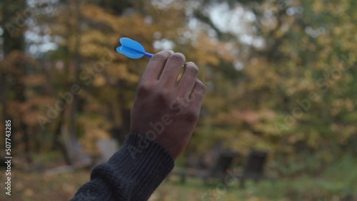 close up of a black man's hand as he throws a dart. photo