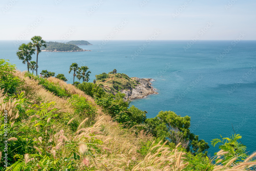 Phuket island Laem promthep cape with coconut palm trees and grass in the foreground beautiful scenery andaman sea in summer season Phuket thailand Beautiful travel background