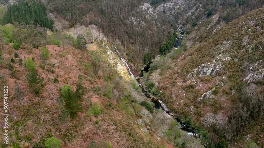 Aerial drone backward moving shot over waterfall in the Sor River at the viewpoint of Aguas Caídas, Manón, Lugo, Galicia, Spain on a cloudy day. Aerial drone backward moving shot over waterfall in the Sor River at the viewpoint of Aguas Caídas, Manón, Lugo, Galicia, Spain on a cloudy day.