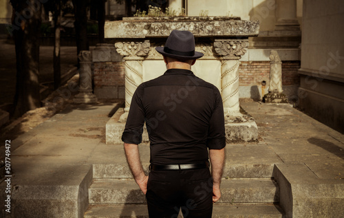 Canvas Print Adult man in black mourning in cemetery