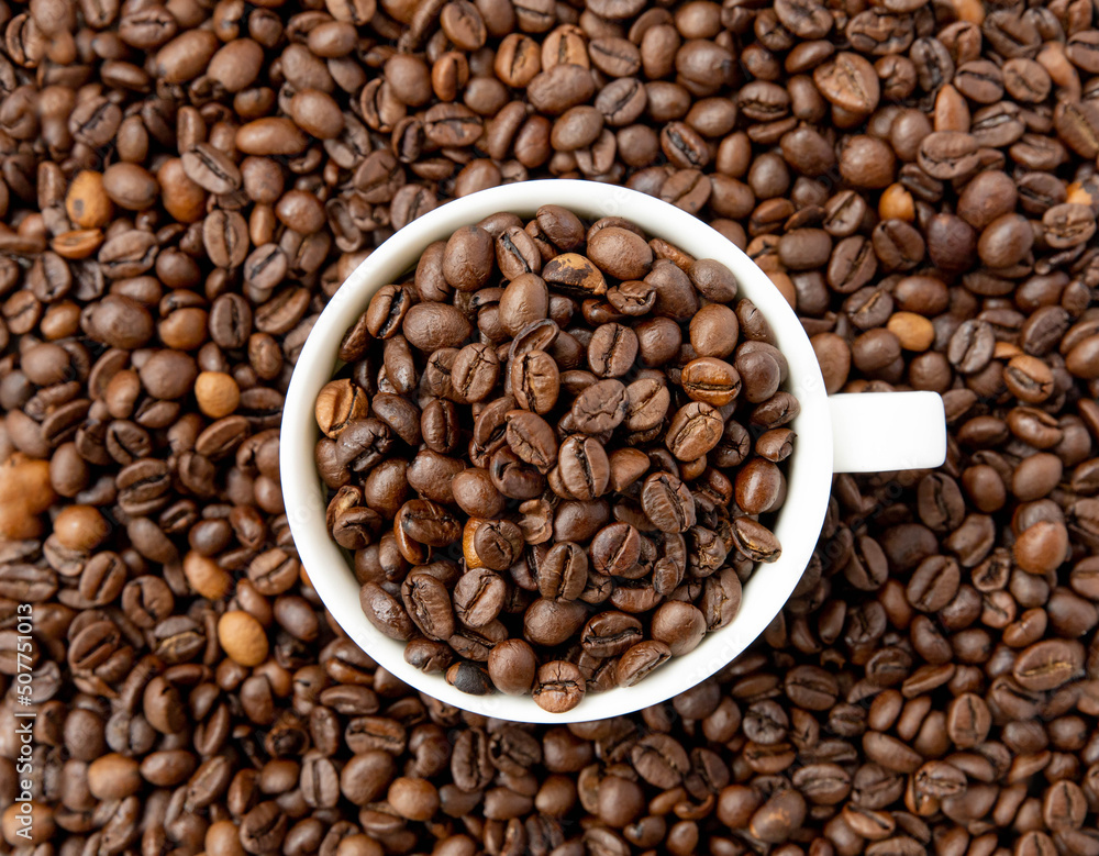 Roasted coffee beans in a white cup, top view Roasted coffee beans in a white cup, top view
