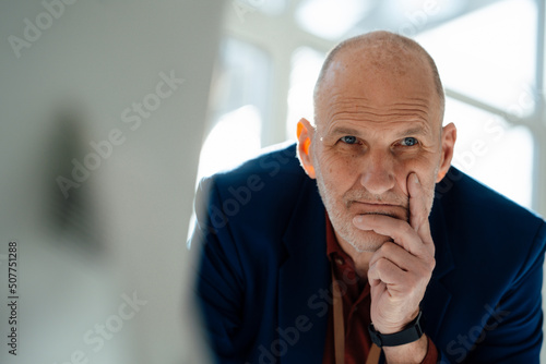 Thoughtful businessman with hand on chin in office photo