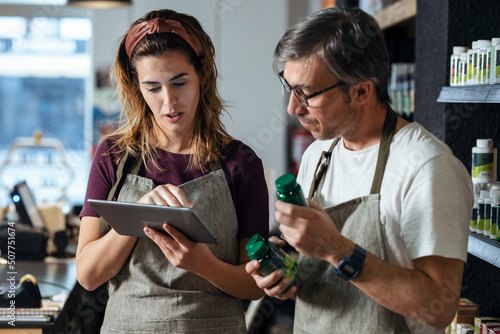 Store owners discussing over tablet PC at organic market