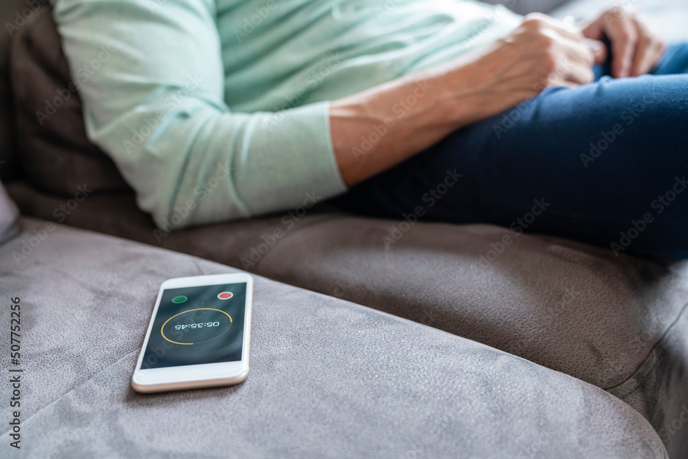 Smart phone with timer by man sitting on sofa at home Smart phone with timer by man sitting on sofa at home