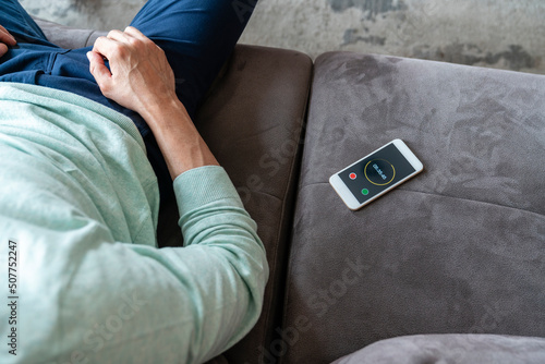 Mobile phone with timer by man sitting on sofa at home