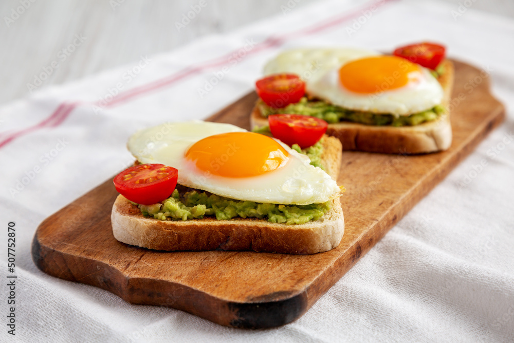 Homemade Healthy Egg, Avocado and Tomato Toast on a rustic wooden board, side view. Homemade Healthy Egg, Avocado and Tomato Toast on a rustic wooden board, side view.