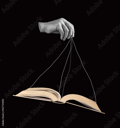 Hand holding book by strings. Using information, facts for manipulation, public influence. Propaganda, conspiracy concept. Black and white. High quality photo photo