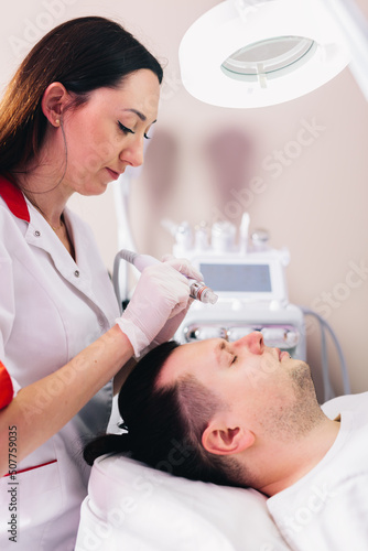 Cosmetologist doing hydrafacial treatment on man face