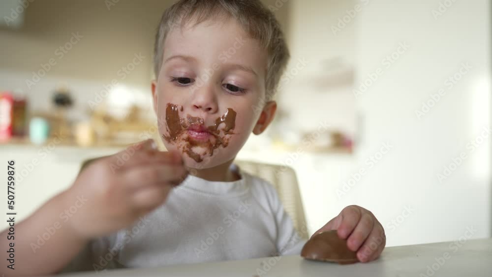 Boy and girl rides cocoa chocolate. Sweet breakfast at table in the kitchen. Dirty face of child. Happy family concept. Cheerful hungry children eat chocolate. Child eat chocolate sitting at table Boy and girl rides cocoa chocolate. Sweet breakfast at table in the kitchen. Dirty face of child. Happy family concept. Cheerful hungry children eat chocolate. Child eat chocolate sitting at table