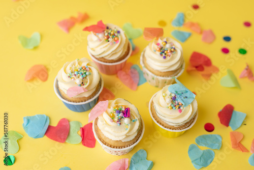 Birthday cupcakes in colorful colors on yellow background