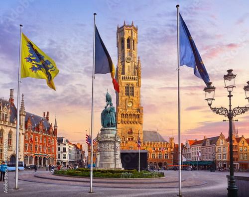 Bruges, Belgium. Market Square (Markt). View to Belfort tower in historical centre of old town and Provincial government building. Evening sunset with scenic sky and clouds.