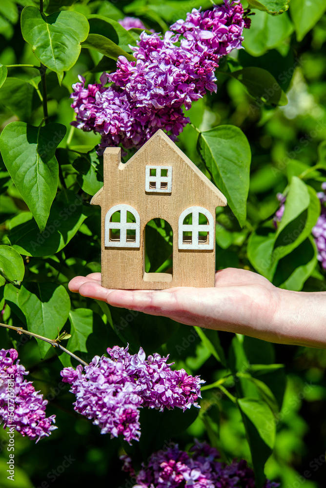 The girl holds in her hand the symbol of the house against the background of blooming lilac
The girl holds in her hand the symbol of the house against the background of blooming lilac