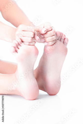 Feet Therapy Concepts. Closeup Image of Soft and Beautiful Female Foot While Hands Touching Toes And Massaging Placed Over Pure White Background.