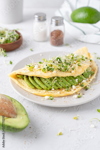 Nice breakfast with avocado. Omelet with microgreens. Gray background with breakfast.
