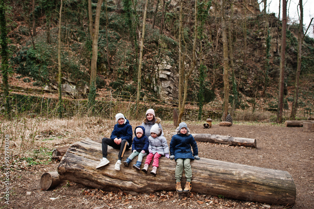 Mother with four children sitting on wood at Znojmo park in Czech Republic Mother with four children sitting on wood at Znojmo park in Czech Republic