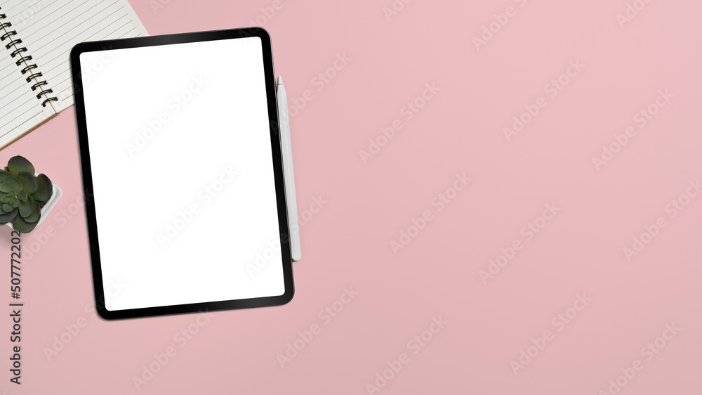 Feminine workplace with digital tablet, notebook and succulent plant on pink background. Top view with copy space Feminine workplace with digital tablet, notebook and succulent plant on pink background. Top view with copy space
