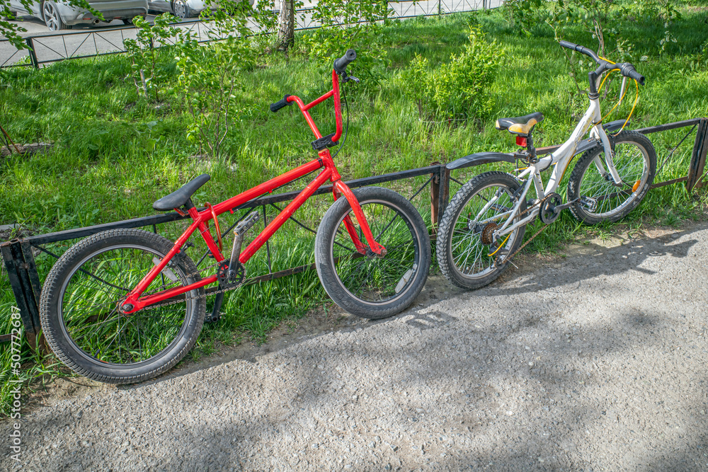 Two bicycles are parked at a metal fence on a spring day
